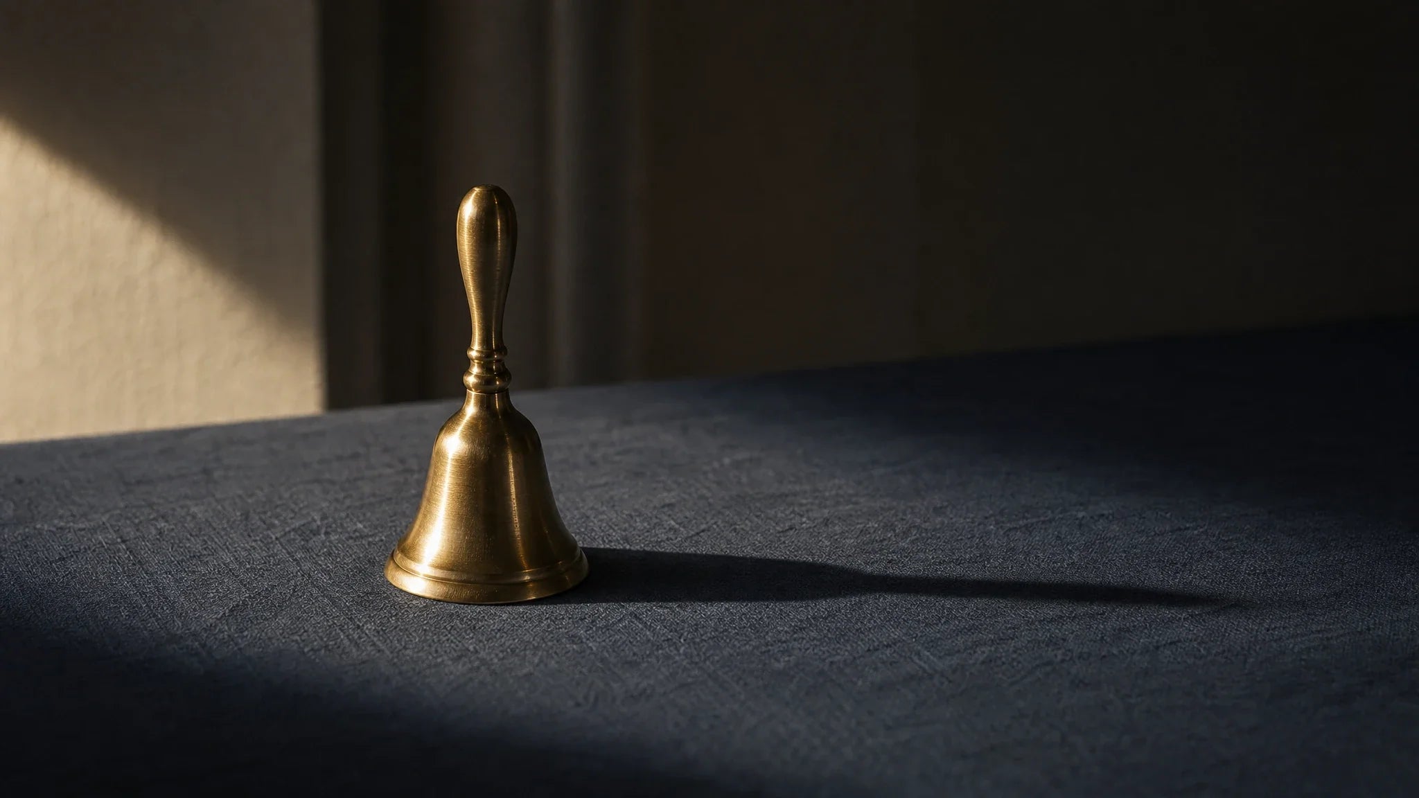 Messingglocke auf schieferblauem Leinen in Abendlicht